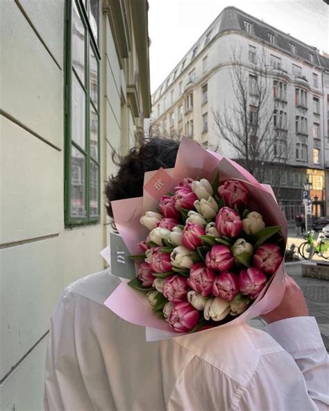 A Person Holding A Bouquet Of Flowers In Front Of A Building On A City