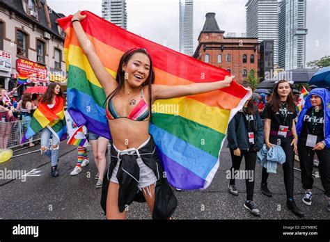 Asian Woman Holding A Rainbow Flag And Wearing A Rainbow Bikini Top During The Toronto LGBTQ