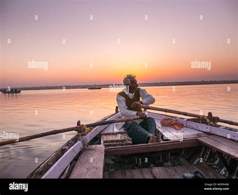 Indian Man Rowing A Boat Down The Ganges River At Down In Varanasi