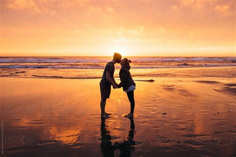 Couple In Love On The Beach Kissing And Holding Hands During Sunset