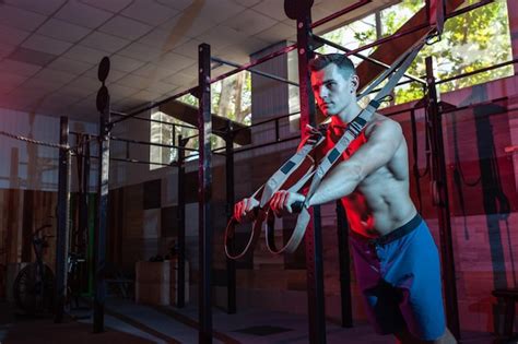 Premium Photo Muscular Man Works Out With The Trx System In A Dark