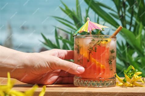 Premium Photo Hand Holds Glass Of Summer Cocktail At Beach Bar