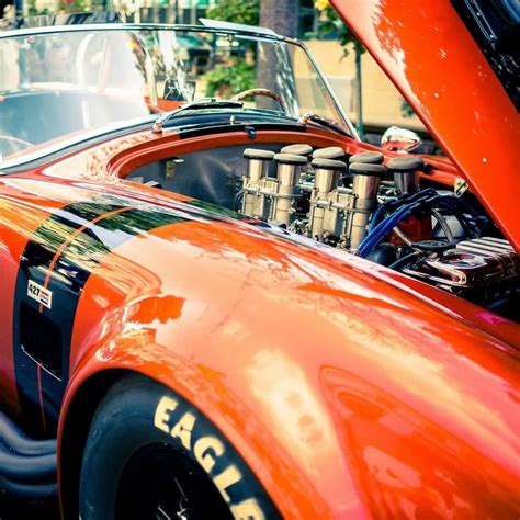 An Orange Sports Car With The Hood Up And Engine In It S Back End