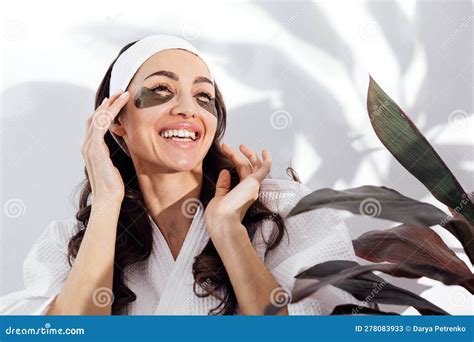 Smiling Woman In A White Bathrobe Takes Care Of Her Skin And Sticking