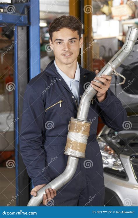 Apprentice Mechanic Holding Exhaust Pipe In Auto Repair Shop Stock