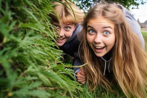 Premium Photo Two Girls Playing Hide And Seek By Tree In Park