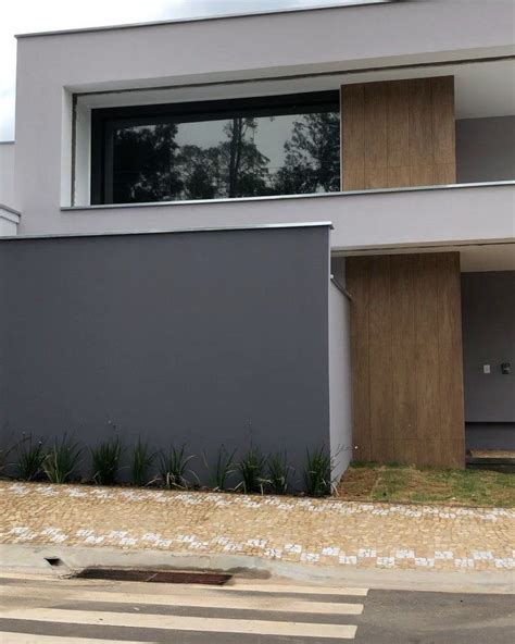 A Modern House With Large Windows And Wooden Shutters On The Front Door