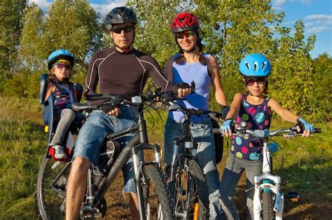 Familia En Bicicleta Al Aire Libre Felices Padres Con Dos Hijos En