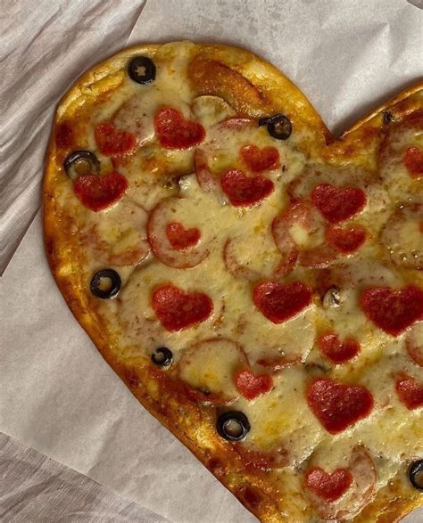 A Heart Shaped Pizza With Pepperoni And Olives