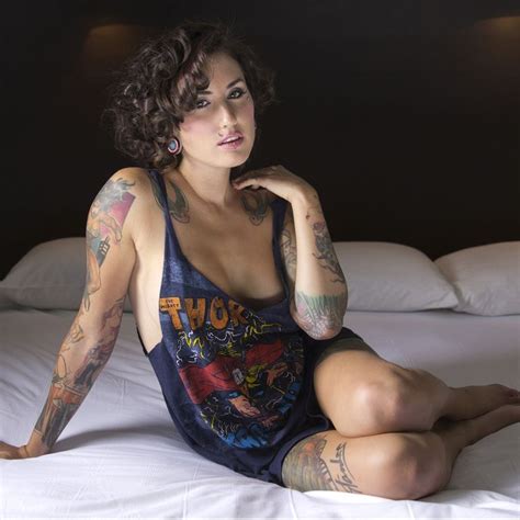 a woman with tattoos sitting on a bed