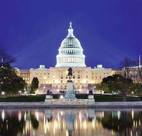 the capitol building is lit up at night with reflecting water and trees ...