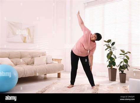 Overweight Mature Woman Stretching At Home Space For Text Stock Photo