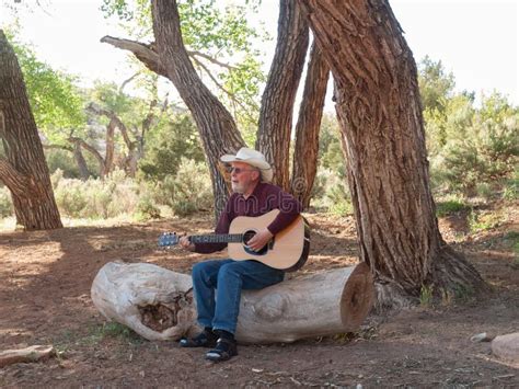 Hombre Que Toca La Guitarra En Un Campo Del Desierto Foto De Archivo