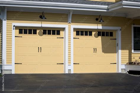 Two Cars Garage Door Painted In Yellow Color In A Typical Single House