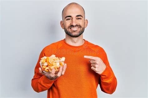 Young Bald Man Holding Potato Chip Smiling Happy Pointing With Hand And