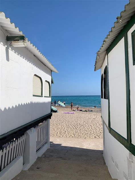 Two Buildings On The Beach With People In The Water And One Building