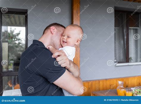 The Father Holds His Son In His Arms And Leans In And Kisses Him