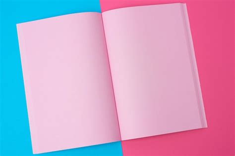 Libro de notas abierto con páginas rosadas en blanco en un fondo azul