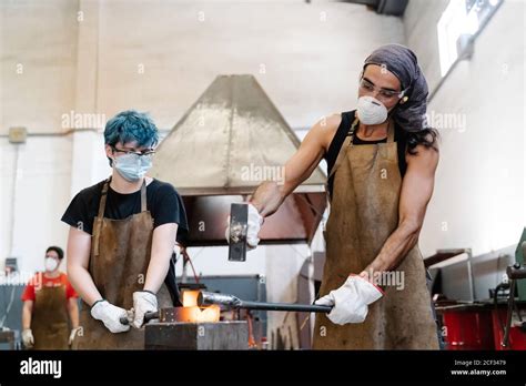 Blacksmiths In Masks Hitting Hot Metal With Hammer While Working Stock Photo Alamy
