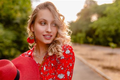 Attraktive stilvolle blonde lächelnde frau in strohrotem hut und bluse sommermode outfit