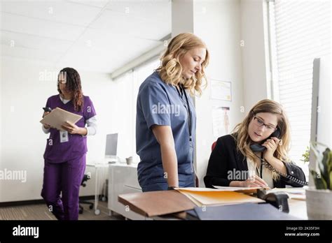 Female Doctor And Nurse With Medical Charts In Clinic Office Stock