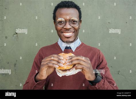 Young Man Eating Cheeseburger Smiling Stock Photo Alamy