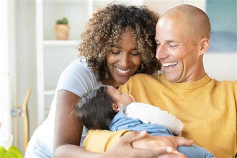 Happy parents smiling at their sleeping baby at home stock photo