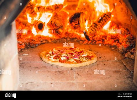 Pizza With Toppings In A Hot Stone Oven With Fire Wood Baking A Delicious Meal Stock Photo Alamy