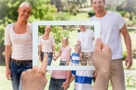 Mão segurando o tablet pc mostrando família adorável no parque Foto