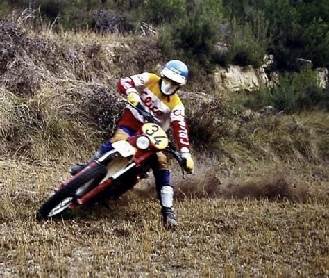 A Man Riding On The Back Of A Dirt Bike Down A Grass Covered Hill Next