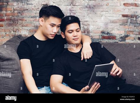 Asian Gay Couple Watching And Looking At Phone Tablet Together Portrait Of Happy Gay Men