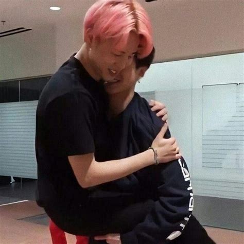 A Man With Pink Hair Hugging A Woman In A Black T Shirt And Red Pants