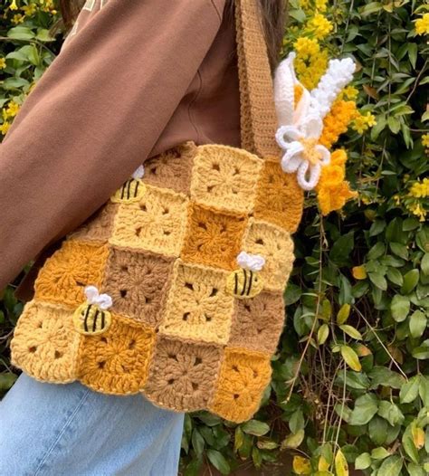 A Woman Carrying A Crocheted Bag With Bees On It And Flowers In The