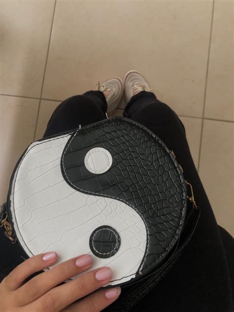 A Woman S Hand Holding A Black And White Purse With A Yin Sign On It