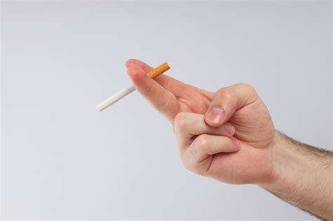 Un Cigarrillo En La Mano De Un Hombre Sobre Un Fondo Claro Foto Gratis