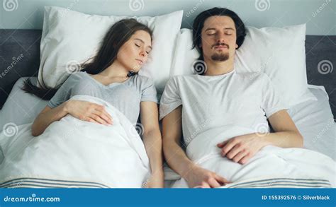 Husband And Wife Sleeping In Bed At Home Covered With Blanket Relaxing