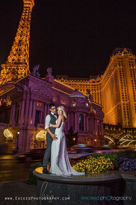 A Bride And Groom Standing In Front Of The Eiffel Tower At Night With Their Arms Around Each Other