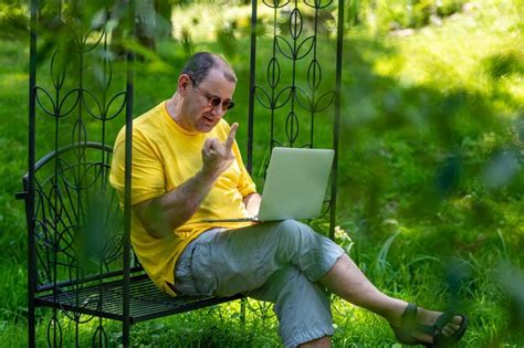 Premium Photo Mature Man With Laptop Working Outside In Garden And Show Fucking Gesture Into