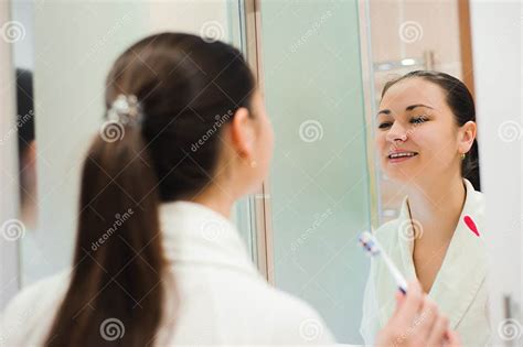 Image Of Pretty Female Brushing Her Teeth In Front Of Mirror Stock