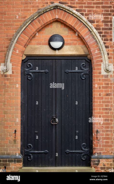 Heavy black wooden church door with iron banding under a brick arch ...