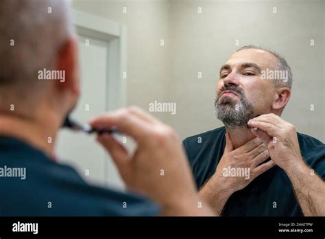Mature Gray Haired Man Restyling His Beard Himself At Home Using Razor