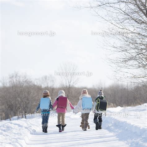 雪道を歩く小学生の後姿の写真素材 124680327 イメージマート