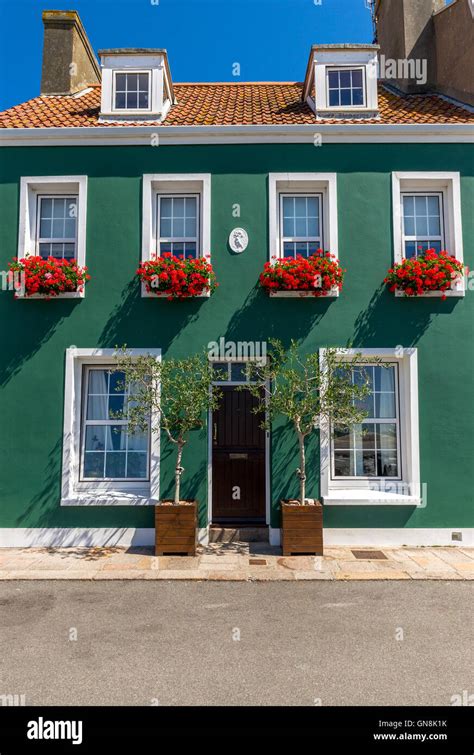 Casa verde pintada con ventana cajas llenas de flores rojas Fotografía