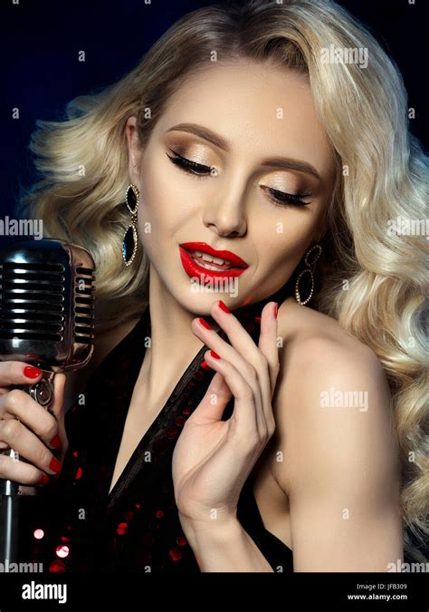 Portrait de jolie blonde chanteuse style rétro holding microphone Beau maquillage avec lèvres