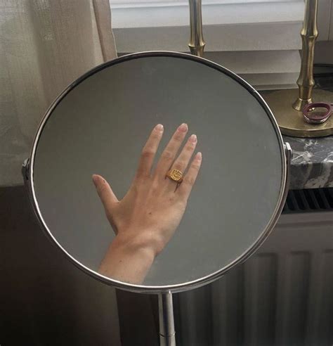 A Person S Hand In Front Of A Mirror With A Gold Ring On It