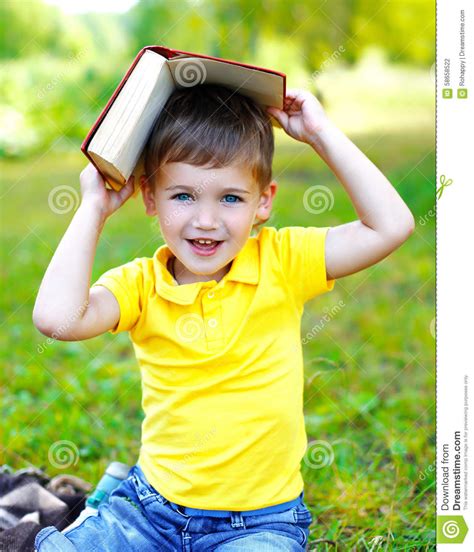 Retrato Do Menino De Sorriso Da Criança O Livro Na Grama No Verão