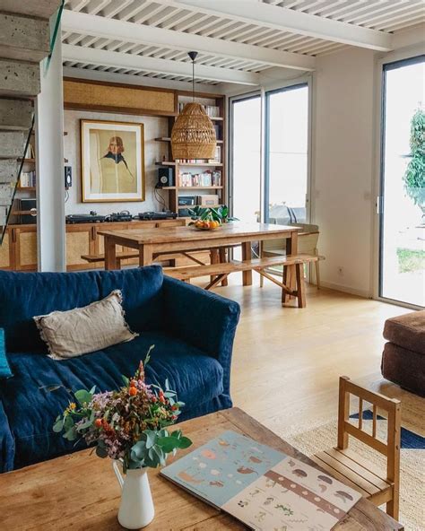 A Living Room With Blue Couches And Wooden Tables In Front Of Large