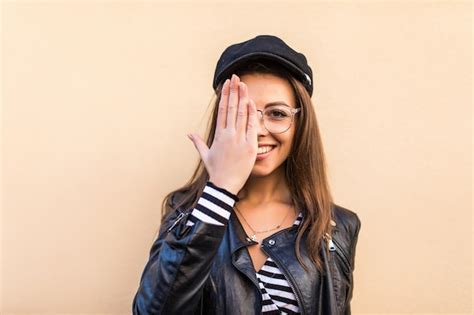 Belle fille de mode en veste de cuir et chapeau noir couvrir son œil de