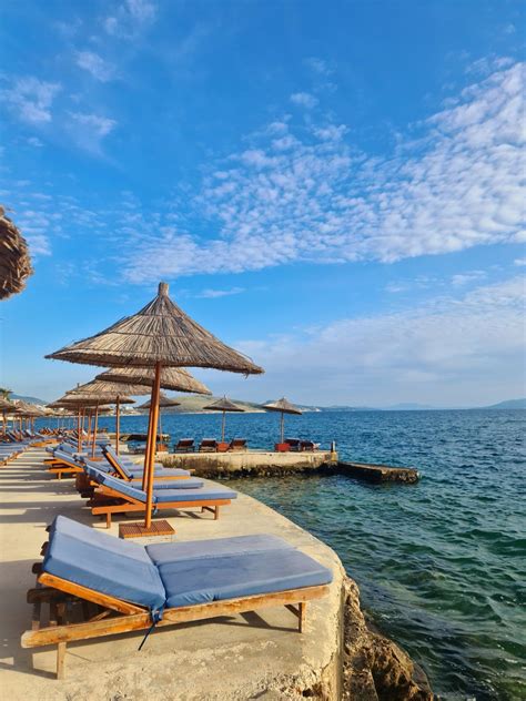 Lounge Chairs And Umbrellas Are Lined Up On The Beach Near The Water S Edge