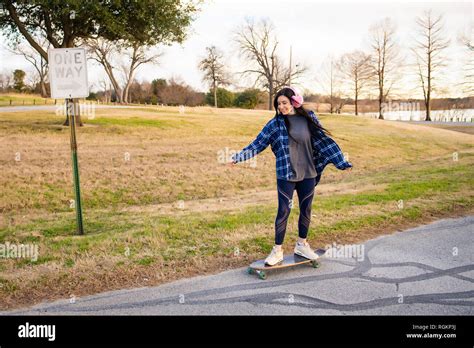 Image Of A Brunette Girl Riding A Skateboard And Enjoying It Stock